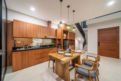 a kitchen with wooden cabinets and a wooden table and chairs at Umaliving Villa Seminyak Bali in Seminyak