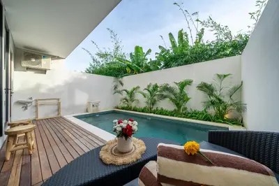 a patio with a swimming pool and a vase of flowers at Umaliving Villa Seminyak Bali in Seminyak