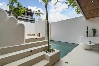 a house with a swimming pool and palm trees at Villa Tibrava Umalas by BaliSuperHost in Canggu