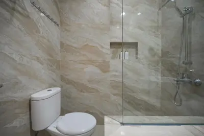 a bathroom with a toilet and a glass shower at Puri Ratu Jimbaran with Private Pool in Jimbaran
