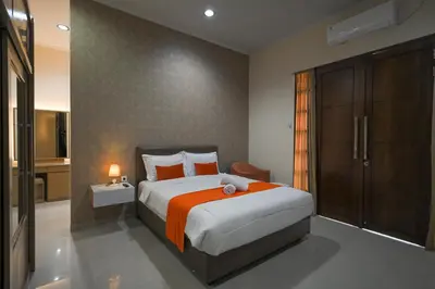 a bedroom with a large bed with an orange blanket at Puri Ratu Jimbaran with Private Pool in Jimbaran