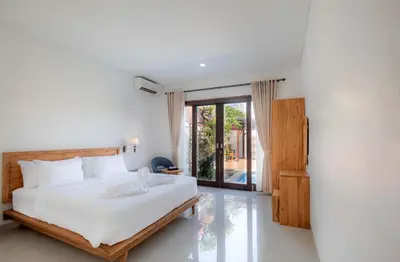a bedroom with a white bed and a sliding glass door at Cherish Villa Umalas in Canggu