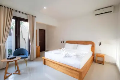 a bedroom with a bed and a blue chair at Cherish Villa Umalas in Canggu