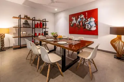 a dining room with a wooden table and white chairs at Villa Alopa Seminyak in Seminyak