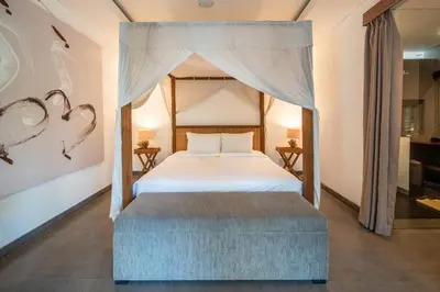 a bedroom with a canopy bed and a ottoman at Villa Alopa Seminyak in Seminyak