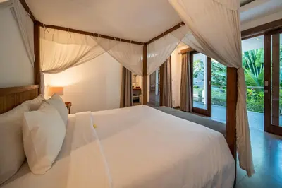 a bedroom with a large white bed with curtains at Villa Alopa Seminyak in Seminyak