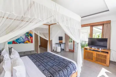 a bedroom with a canopy bed and a television at Villa Alopa Seminyak in Seminyak