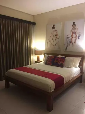 a bedroom with a bed with two paintings on the wall at Villa Bteega sawah in Seminyak