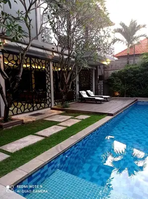 a swimming pool in front of a house at Villa Bteega sawah in Seminyak