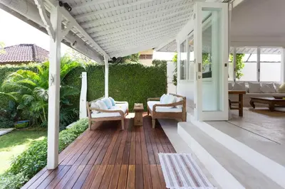 a porch with chairs and a wooden deck at Bear Cottage 4 Bedroom Luxury Villa - Petitenget, Seminyak in Seminyak