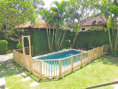 a fence around a swimming pool in front of a house at Bear Cottage 4 Bedroom Luxury Villa - Petitenget, Seminyak in Seminyak