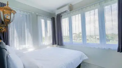 a bedroom with a white bed and large windows at Rumah Jimbaran Kuta 3 bedroom 9 pax SukaBali 1 in Jimbaran