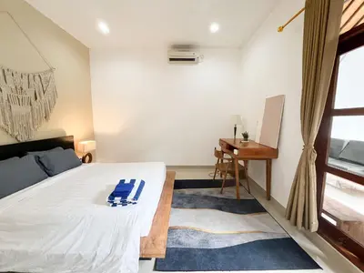 a bedroom with a bed and a desk and a window at Villa Kita Seminyak in Seminyak