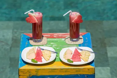two plates of fruit on a table with drinks at Villa Sky Li by Nagisa Bali in Seminyak