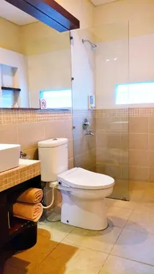 a bathroom with a toilet and a glass shower at Maya Kori Villa in Jimbaran