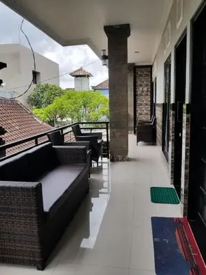 a balcony with a couch and chairs on a building at Jepun Segara Guest House in Kuta