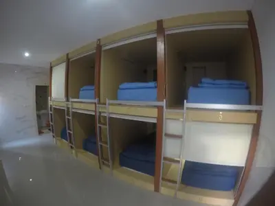 a room with four bunk beds with blue beds at Jepun Segara Guest House in Kuta