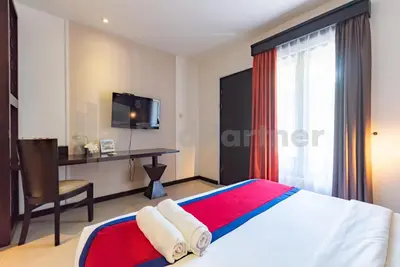a hotel room with a bed and a desk at Ozz Hotel Kuta Bali manage by Ozz Group in Kuta