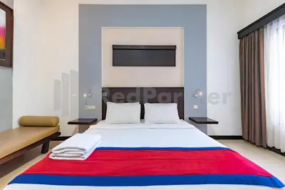 a bedroom with a large bed with a red and blue blanket at Ozz Hotel Kuta Bali manage by Ozz Group in Kuta