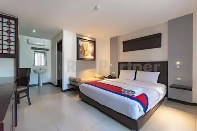 a bedroom with a large bed and a desk and chair at Ozz Hotel Kuta Bali manage by Ozz Group in Kuta