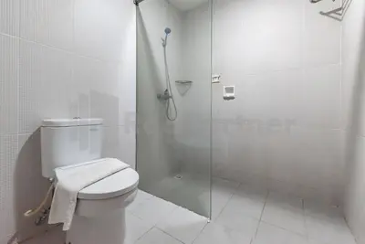 a white bathroom with a shower and a toilet at Ozz Hotel Kuta Bali manage by Ozz Group in Kuta