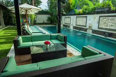 a swimming pool with green chairs and a table and a pool at Villa Dewata II in Seminyak