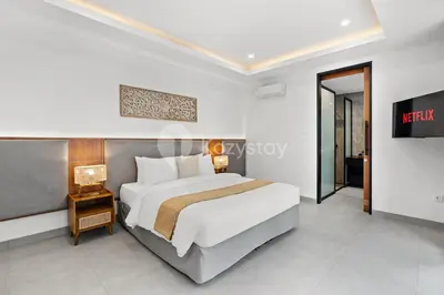 a bedroom with a large bed and a tv at Kros Villa by Kozystay - Legian in Legian