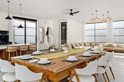 a dining room with a large wooden table and white chairs at Kros Villa by Kozystay - Legian in Legian
