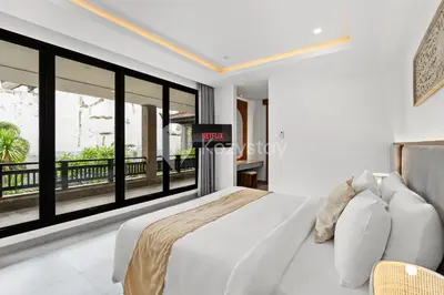 a bedroom with a white bed and large windows at Kros Villa by Kozystay - Legian in Legian