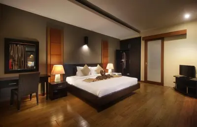 a bedroom with a bed and a desk and a television at Jayani Villa Seminyak byFaba in Seminyak