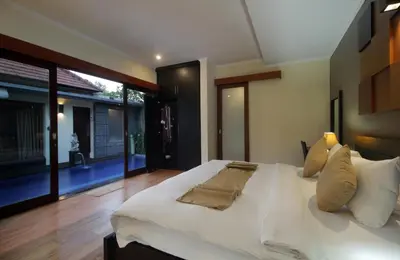 a bedroom with a large white bed with a large window at Jayani Villa Seminyak byFaba in Seminyak
