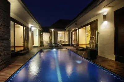 an indoor swimming pool in a house at night at Jayani Villa Seminyak byFaba in Seminyak
