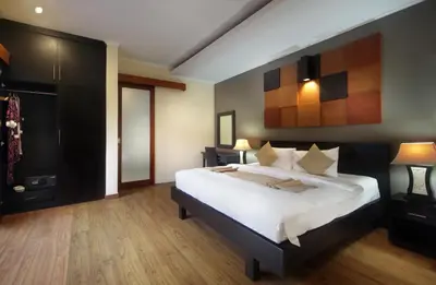a bedroom with a large bed and wooden floors at Jayani Villa Seminyak byFaba in Seminyak