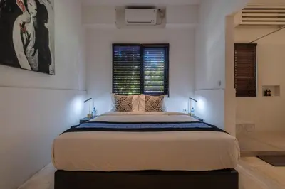 a large bed in a white room with two windows at Villa Samudra Raya in Seminyak