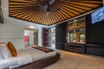 a bedroom with a large bed with a ceiling fan at Villa Samudra Raya in Seminyak