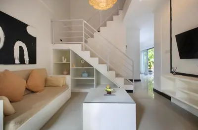 a living room with a couch and a staircase at Zowa Villa Seminyak byFaba in Seminyak