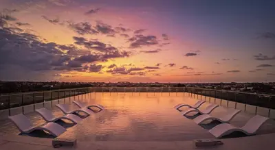 a group of white lounge chairs sitting on top of a pool at The Two Umalass in Canggu