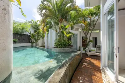 an indoor pool with palm trees in a house at Modern 2BR Villa with Private Pool Prime Location in Seminyak