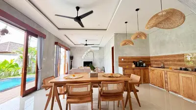 a kitchen with a wooden table and some chairs at Villa Bumbabu in Kerobokan