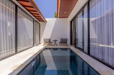 a house with a swimming pool with two chairs and windows at Villa Phoenix Brand New 1BR in Umalas, Bali in Seminyak