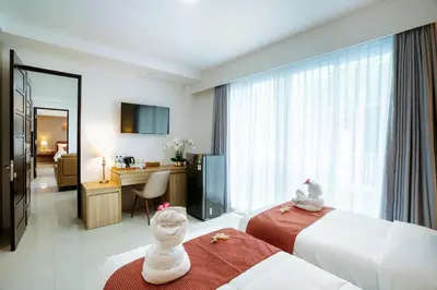 a hotel room with two beds and a desk at Grand Inkuta in Seminyak
