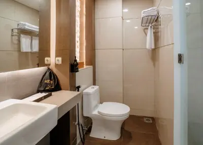 a bathroom with a white toilet and a sink at Grand Inkuta in Seminyak