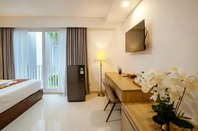 a hotel room with a bed and a desk with flowers at Grand Inkuta in Seminyak