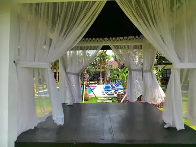 a gazebo with white curtains and a yard at D'Mell Bali in Nusa Dua