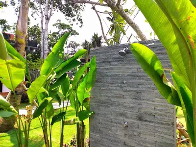 a brick wall with green plants next to it at D'Mell Bali in Nusa Dua