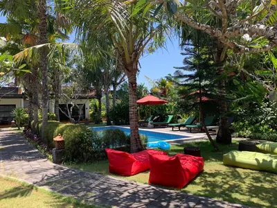a resort yard with red pillows and a swimming pool at D'Mell Bali in Nusa Dua
