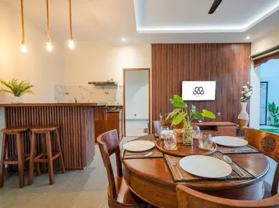 a dining room with a wooden table and chairs at Metta Villa in Jimbaran