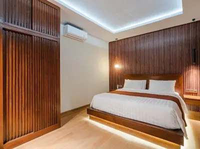 a bedroom with a large bed with a wooden wall at Metta Villa in Jimbaran