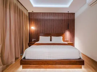 a bedroom with a large bed with a wooden headboard at Metta Villa in Jimbaran