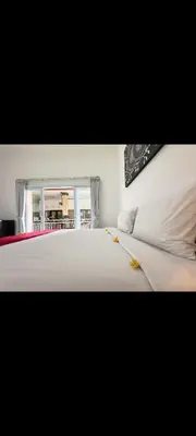 a bedroom with a large white bed and a window at narayuka house kamar 3 in Seminyak